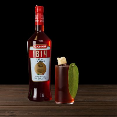 Bottiglia di Casoni 1814 Bitter con cocktail su tavolo di legno, un esempio di video ricetta di Drinkography che valorizza il prodotto del brand.